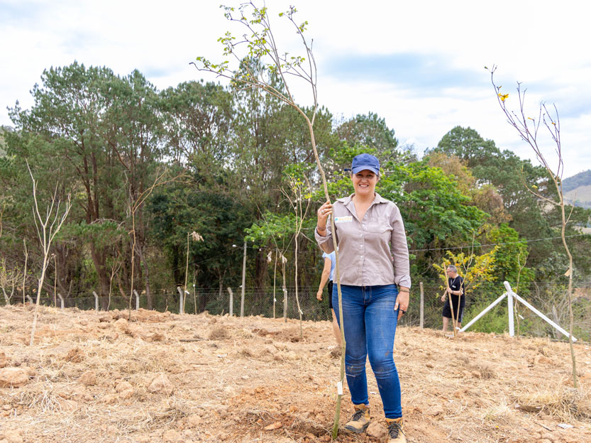 Foto com Ana Paula Balderi (Coordenadora de Restauração Ecológica da Copaíba) ao lado de uma muda de árvore na unidade de lazer Serra Negra.
